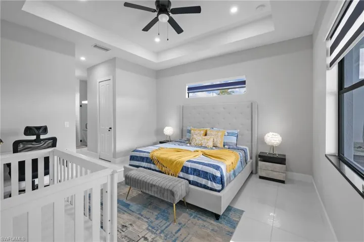Tiled bedroom with a raised ceiling, recessed lighting, a closet, and ceiling fan