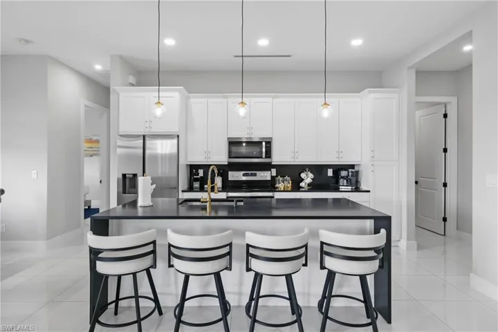 Kitchen with appliances with stainless steel finishes, a center island with sink, white cabinets, recessed lighting, and backsplash