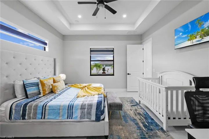 Bedroom featuring multiple windows, a raised ceiling, light tile patterned flooring, and recessed lighting