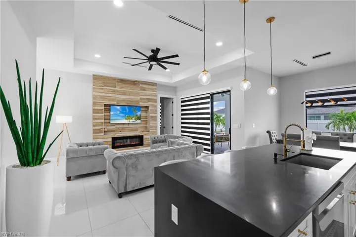 Kitchen featuring a center island with sink, open floor plan, hanging light fixtures, light tile patterned flooring, and a fireplace
