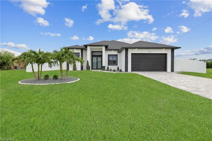 Prairie-style home with stucco siding, an attached garage, and decorative driveway