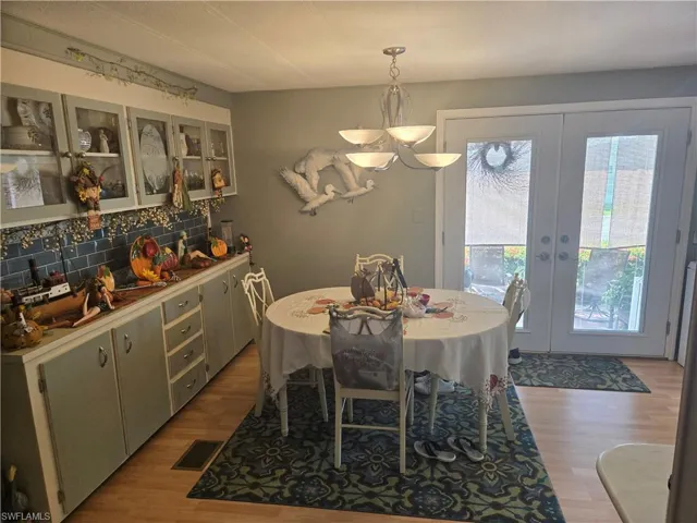 Dining space with french doors, a notable chandelier, and light wood-type flooring