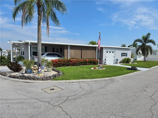 View of front of house with a front yard, a garage, and a carport