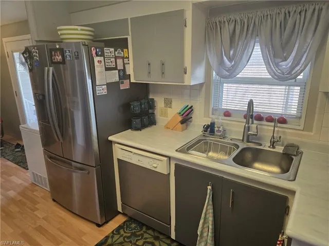 Kitchen featuring decorative backsplash, appliances with stainless steel finishes, sink, and light wood-type flooring