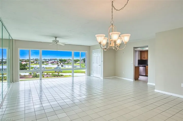 Living Room featuring light tile patterned floors, a chandelier, a water view, and ceiling fan