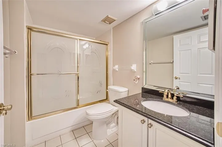 Bathroom with shower / bath combination with glass door, vanity, and light tile patterned flooring