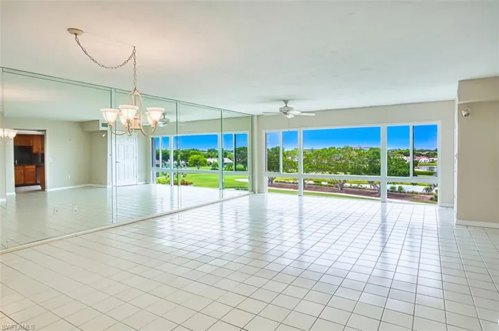 Living Room with light tile patterned floors, healthy amount of natural light, a chandelier, and ceiling fan