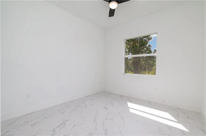 Unfurnished room with light marble finish floors and a ceiling fan