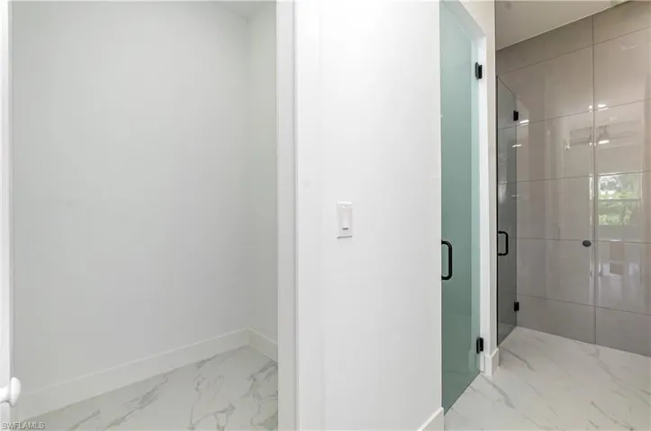 Full bathroom featuring light marble finish floors and a stall shower