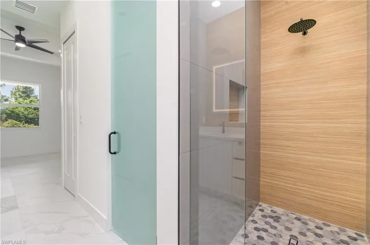 Full bath with a shower stall, ceiling fan, and light marble finish floors