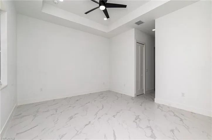 Spare room featuring light marble finish floors, ceiling fan, recessed lighting, and a raised ceiling