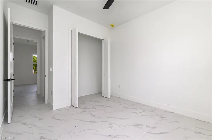 Unfurnished bedroom featuring light marble finish flooring and a ceiling fan