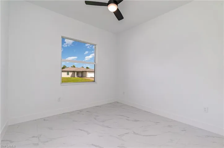 Empty room with light marble finish floors and a ceiling fan