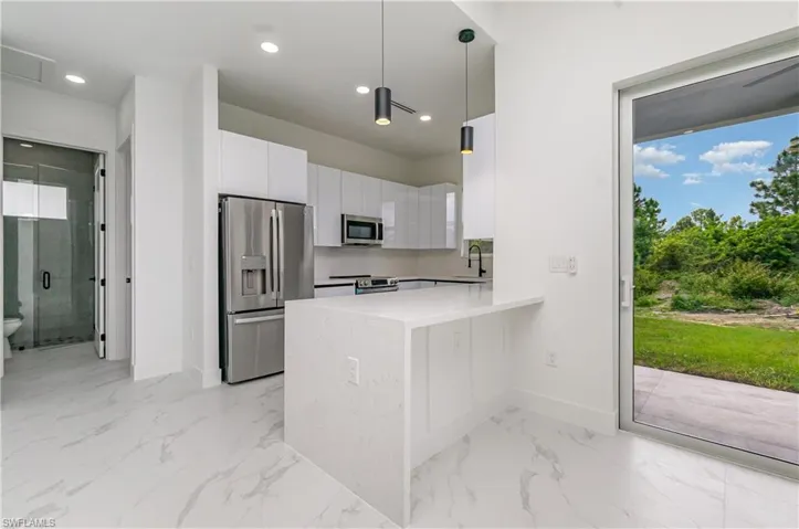 Kitchen featuring pendant lighting, stainless steel appliances, white cabinets, a peninsula, and modern cabinets