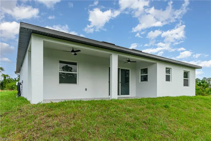 Rear view of property featuring a yard, ceiling fan, a patio area, and stucco siding