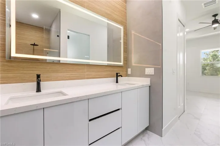 Full bathroom with double vanity, recessed lighting, ceiling fan, and light marble finish flooring