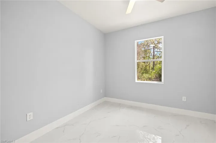 Empty room featuring light marble finish flooring and ceiling fan