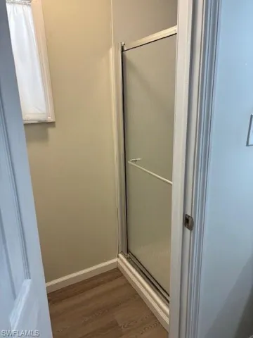 Bathroom with a shower stall, baseboards, and wood finished floors