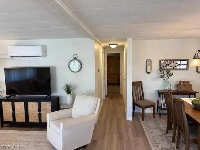 Living area with an AC wall unit and wood finished floors