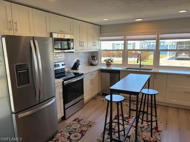 Kitchen featuring light countertops, white cabinets, stainless steel appliances, and a sink