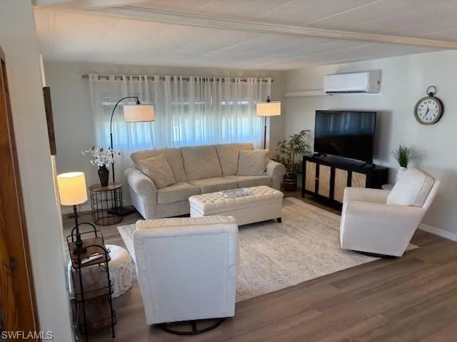 Living room featuring a wall mounted AC, wood finished floors, and baseboards