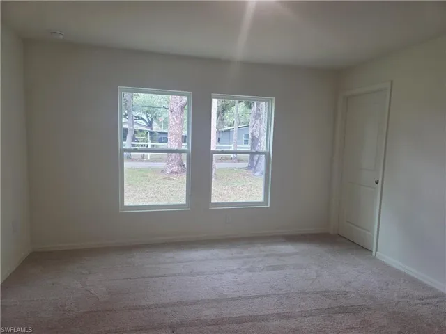 Empty room featuring light colored carpet and baseboards