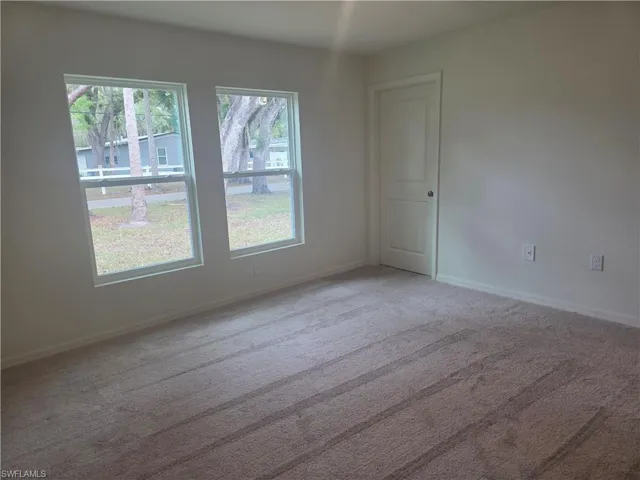 Spare room featuring healthy amount of natural light and light carpet