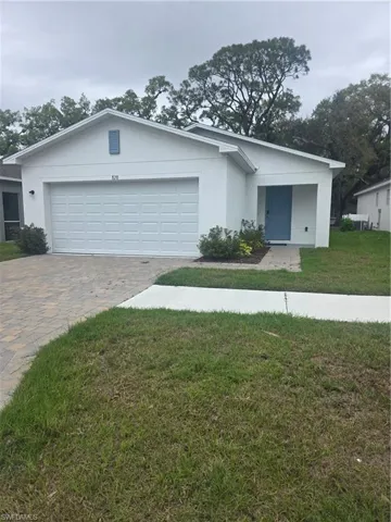 Single story home featuring a front lawn, stucco siding, decorative driveway, and an attached garage