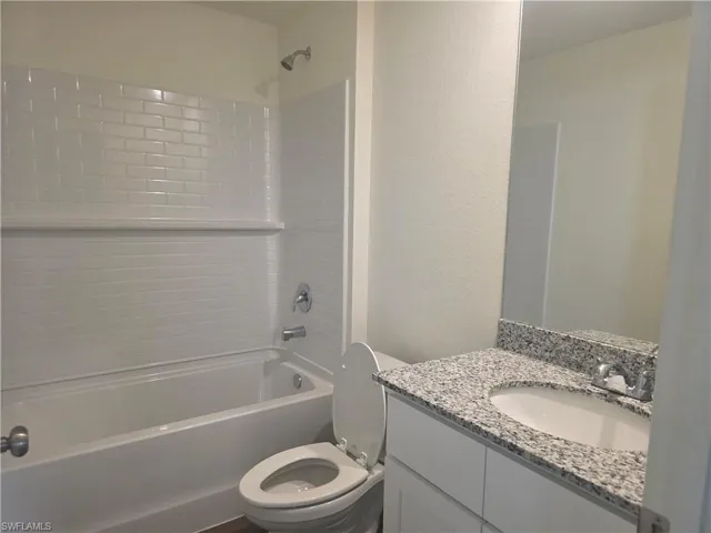 Bathroom featuring a textured wall, vanity, and bathing tub / shower combination