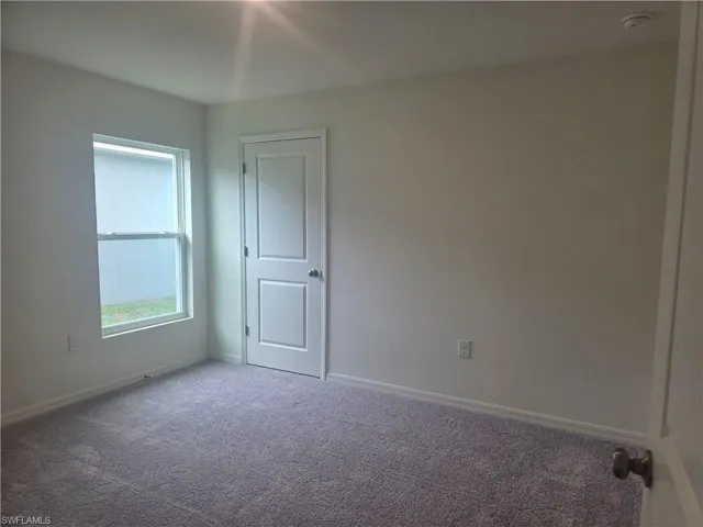 Empty room featuring carpet flooring and baseboards