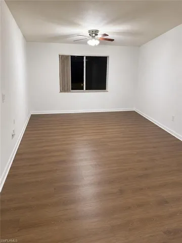 Spacious room featuring wood-finish flooring, white baseboards, and a neutral color palette