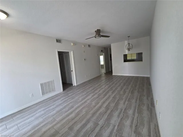 Unfurnished living room featuring wood tiled floors, a ceiling fan, and a textured ceiling