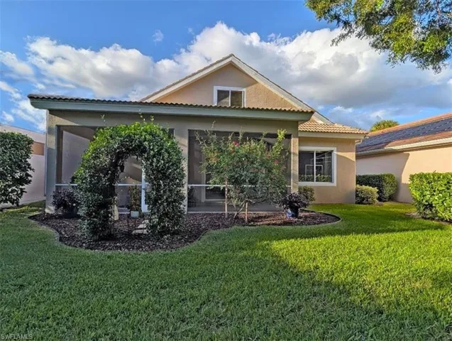 Back of property featuring stucco siding, a yard, a tile roof, and a sunroom