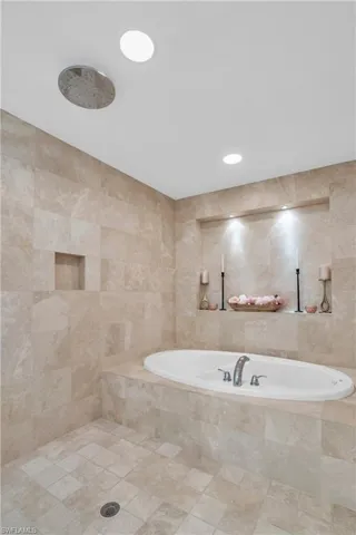 Bathroom featuring tile floors, shower with separate bathtub, and tile walls