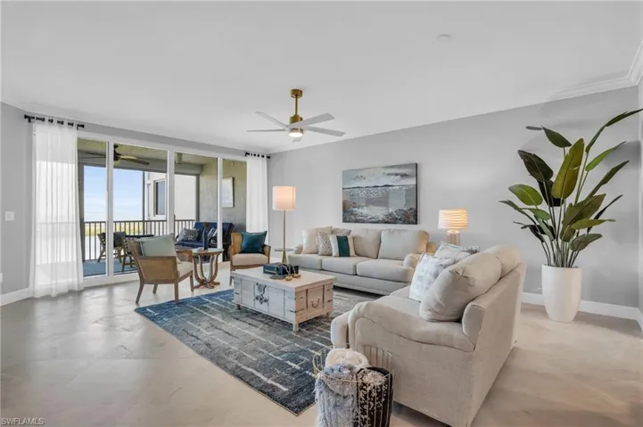 Living room featuring ornamental molding, ceiling fan, and light tile floors