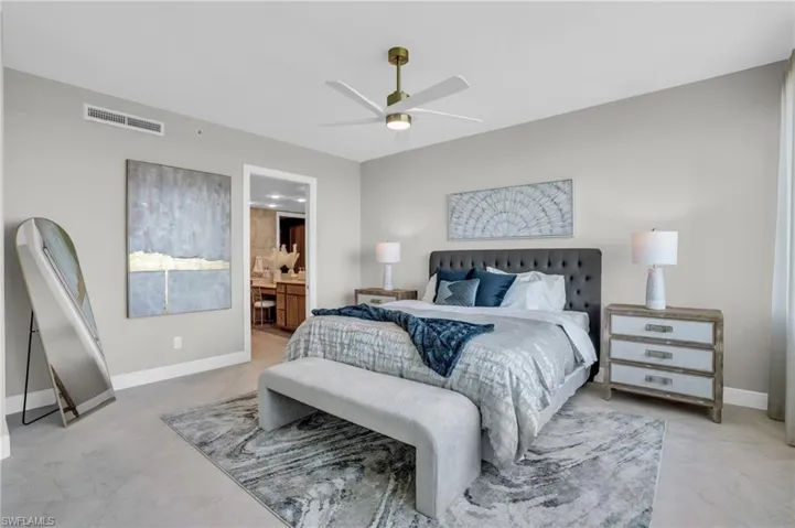 Bedroom featuring ceiling fan, light tile flooring, and ensuite bath