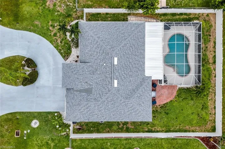 Property featuring a shingle roof, a screened-in pool, and a curved concrete driveway