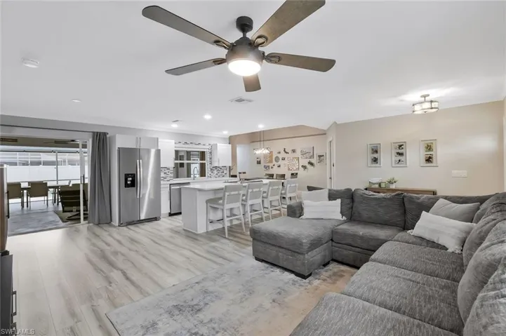 Open-concept living area featuring light wood-finish flooring, recessed lighting, and a contemporary ceiling fan