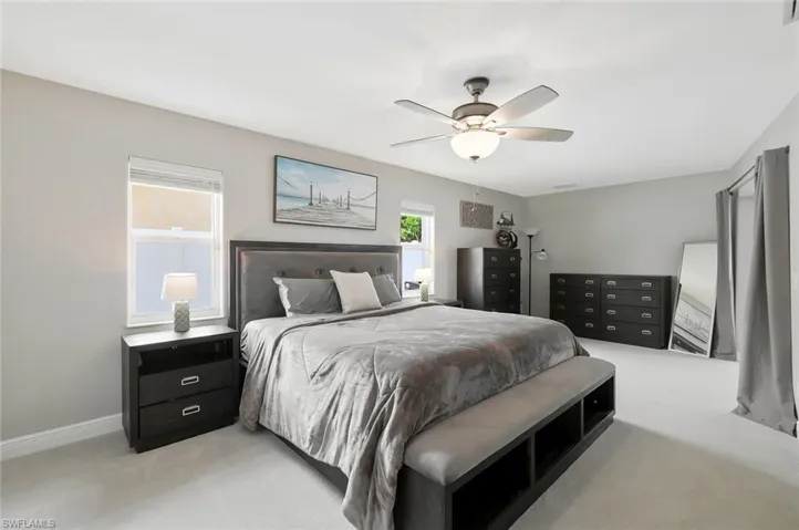 Spacious bedroom featuring light-toned carpeting and multiple windows