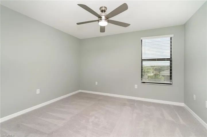 Empty room with light colored carpet and ceiling fan