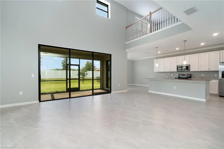 Unfurnished living room with plenty of natural light, a high ceiling, light tile patterned floors, ornamental molding, and recessed lighting