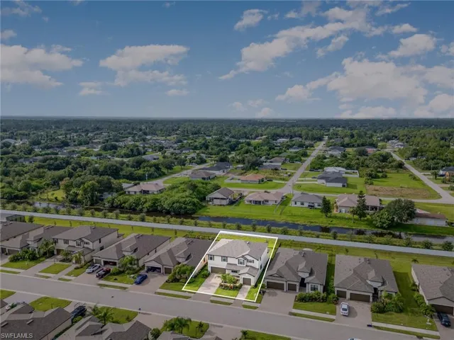 Aerial view of residential area featuring property boundaries highlighted and a nearby body of water