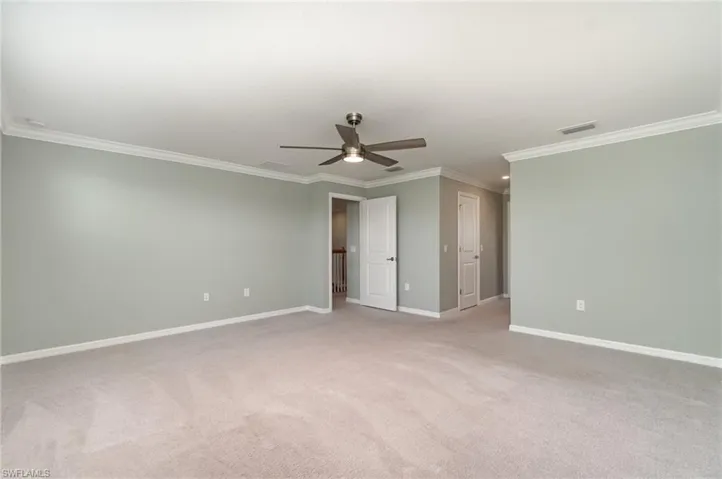 Unfurnished bedroom featuring crown molding, light colored carpet, ceiling fan, and a closet