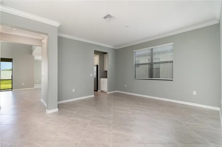 Spare room with ornamental molding and light tile patterned floors