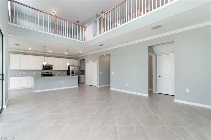 Unfurnished living room with a towering ceiling, ornamental molding, light tile patterned floors, and recessed lighting