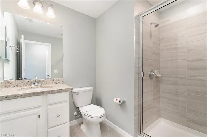 Bathroom featuring vanity, a shower stall, and light tile patterned floors