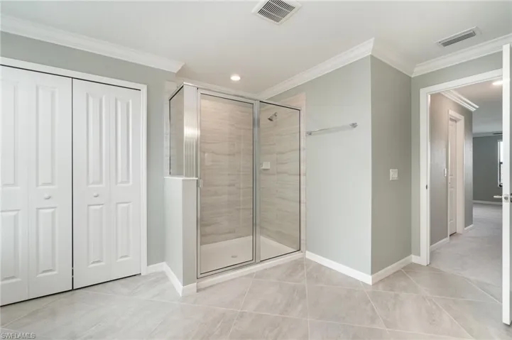 Bathroom featuring a stall shower, a closet, crown molding, recessed lighting, and light tile patterned floors