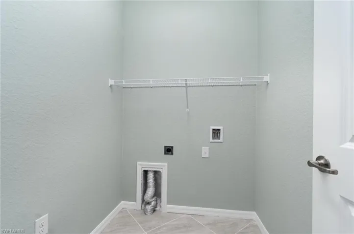 Laundry room with hookup for an electric dryer, tile patterned floors, washer hookup, and a textured wall