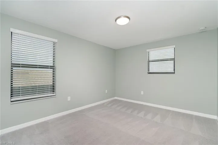 Empty room with light colored carpet and baseboards