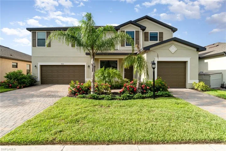 Traditional-style house with decorative driveway, stucco siding, a front yard, and an attached garage